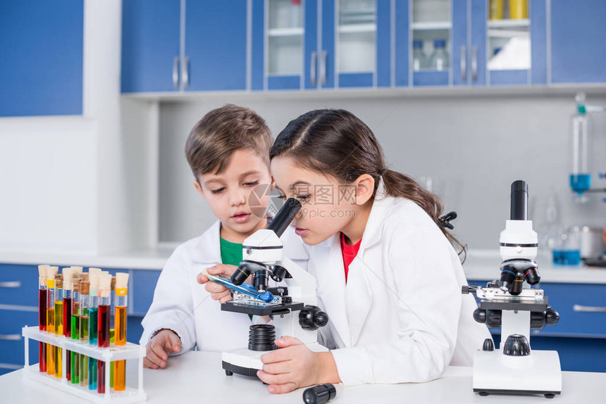 在化学实验室使用显微镜穿白外套的小男图片