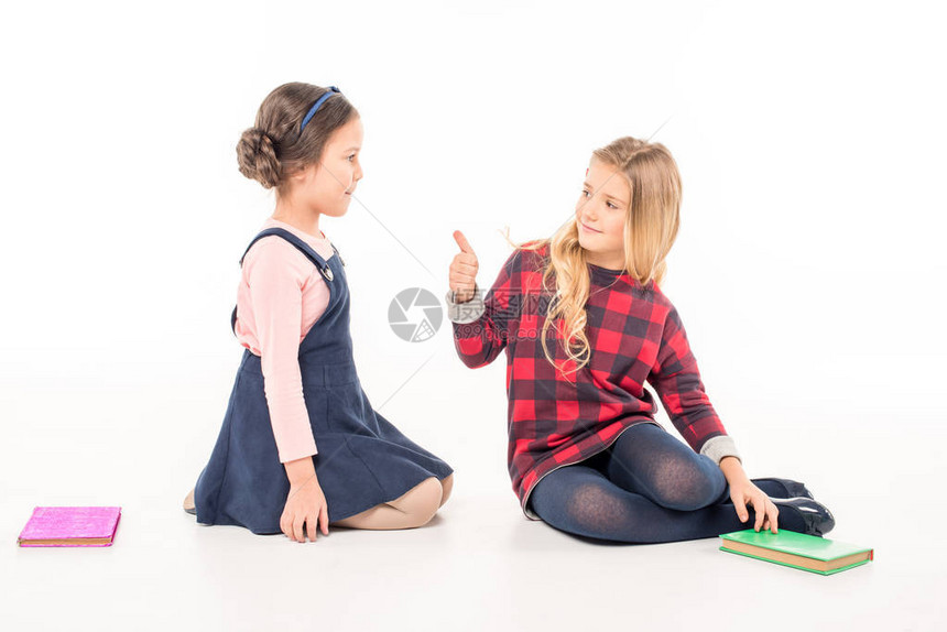 两个女学生坐在书本旁图片