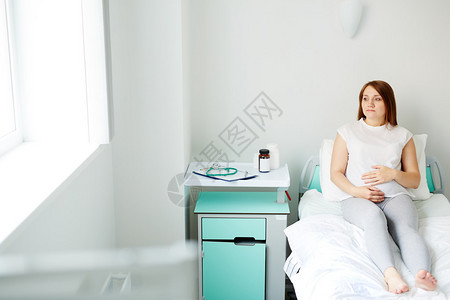 年轻孕妇坐在医院的床上图片