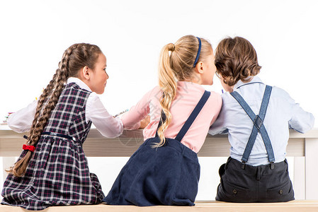 坐在书桌边的学童背对面用白背景图片