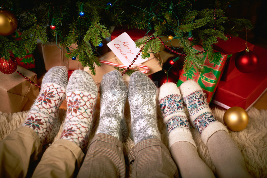 圣诞树旁穿着羊毛袜的人脚图片