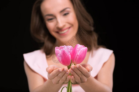 带着美丽的粉红郁金香的年轻微笑的女士孤立在黑人国际背景图片