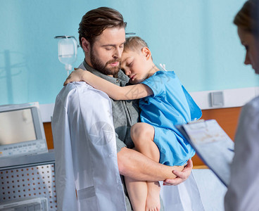 年轻父亲在医院看医生时抱着小儿图片