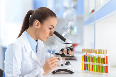 集中的女科学家在实验室与显微镜背景图片