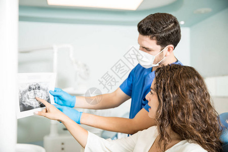 在牙科诊所向女病人提供显示X光牙齿的图片