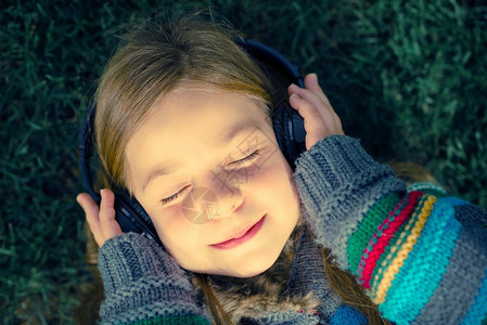 女孩无线耳机享受音乐在公园图片