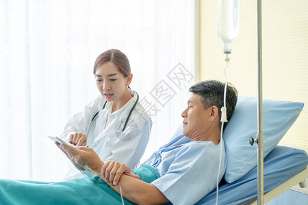 亚洲女医生坐在病床上与老年患者讨论图片