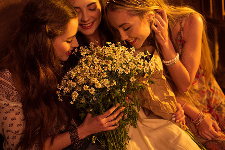 三个笑着的年轻女子身穿博霍风格闻着香菊高清图片