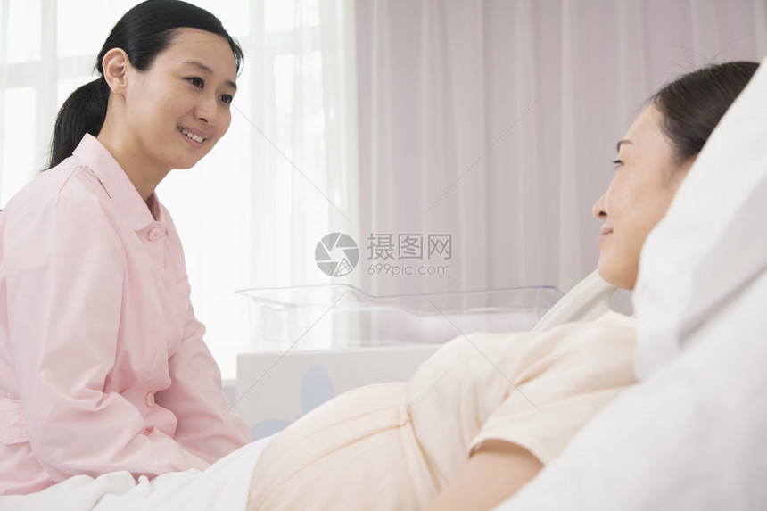 微笑的护士与躺在医院床上的孕妇交图片