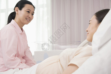 微笑的护士与躺在医院床上的孕妇交图片