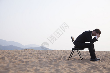 商人坐在沙漠中间头顶着头坐着图片