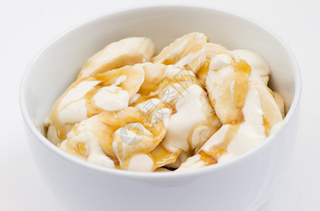 用酸奶和蜂蜜盖住碗里的香蕉片特写图片