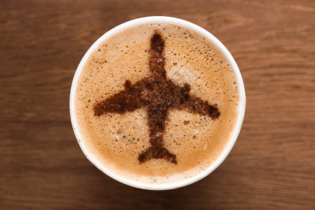 在木制桌面上挂有飞机标志的咖啡杯顶部视图片