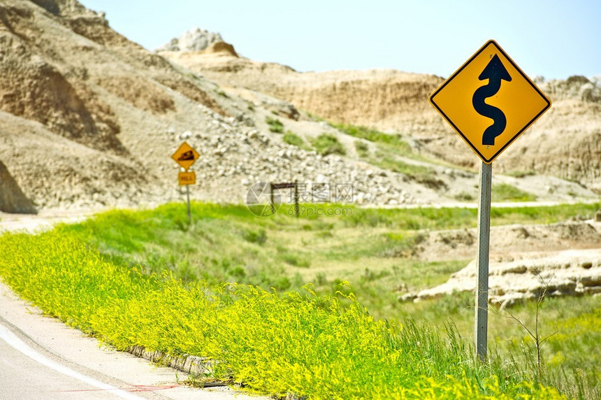 弯曲的荒地道路和警告标志图片