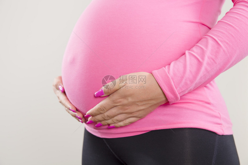 一个孕妇紧抓住她肚子肿胀的手图片