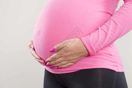 一个孕妇紧抓住她肚子肿胀的手图片
