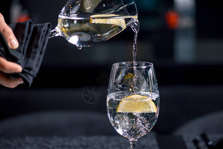 用柠檬工艺将水倒入玻璃杯中的近景图片