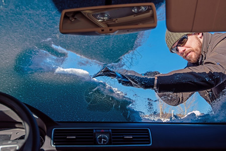 男人从雪和冰之后清洗车挡风玻璃图片