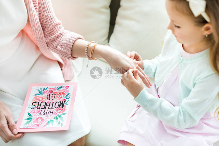 在母亲节将首饰放在母亲手上的可爱小女孩的部分景象图片