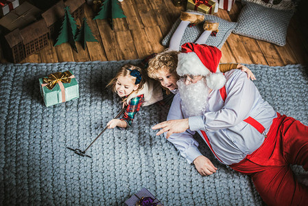 圣诞快乐的圣诞老人带着孩子躺在地图片