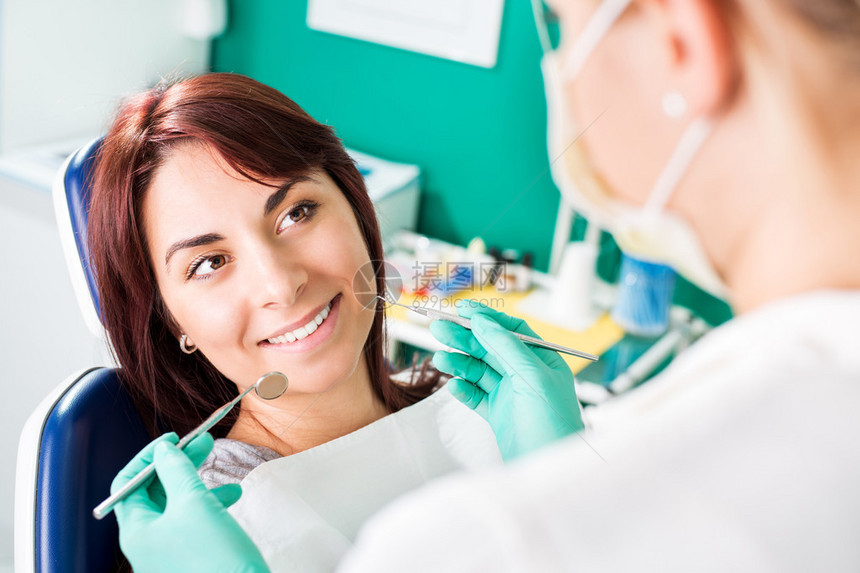 坐在牙医椅子上看牙医时微笑着的妇女准备图片