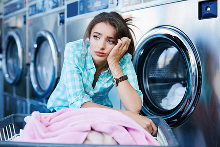 女人靠近一篮子衣服和洗衣机图片