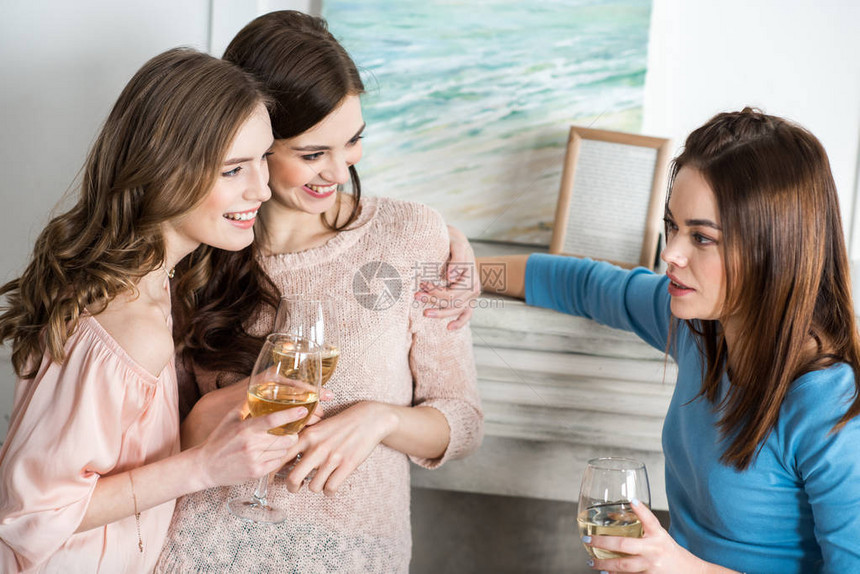 三名有吸引力的年轻女子带着白葡萄酒图片