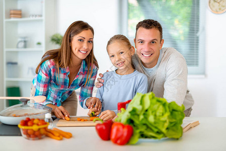 美丽的年轻家庭在国内厨房烹饪健康的饭菜图片