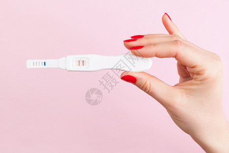 美丽的女手与指甲持有积极的妊娠试验孤立在粉的孕产怀孕节育概念最小稀疏图片