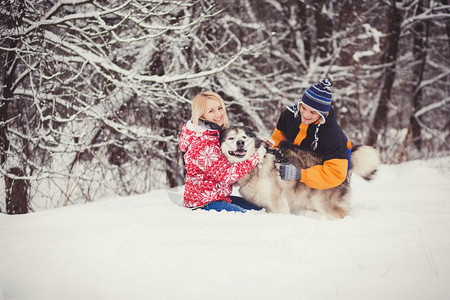 幸福的情侣和狗在冬天的森林里玩耍图片
