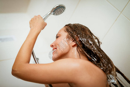 快乐的淋浴女人洗脸和头发在淋浴头图片