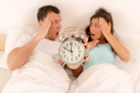 床上的年轻夫妇觉醒了闹钟响起图片