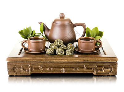 粘土茶壶和杯子在木三脚架上的静物白图片