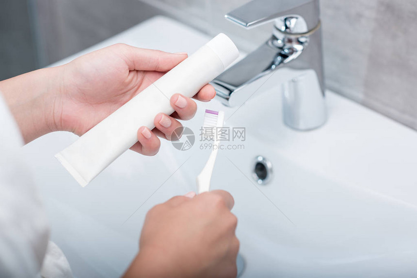 将牙刷和牙膏握在手中的妇图片