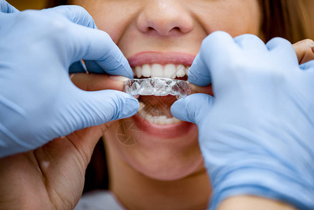 近视牙医向女病人展示如何使用流动矫形器械进行牙科矫正的图片