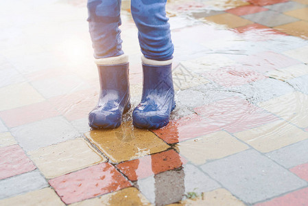 雨后穿着橡胶靴的孩子在水坑里跳跃的脚图片