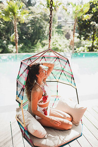 穿着白色泳衣的女人在豪华酒店的游泳池边玩着吊椅摇摆图片