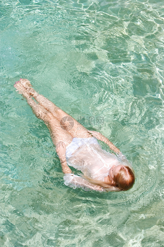 一个年轻女子在健康水疗游泳池清澈透明的蓝色海水中游泳图片