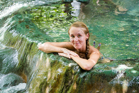 在泰国南部Krabi温泉瀑布下健康浴场的年轻女游客图片