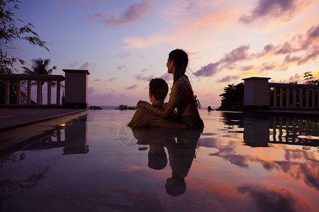 日落时在游泳池里放松的夫妇图片