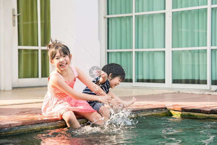 亚洲儿童在阳光炎热的夏日在游泳池里喷图片