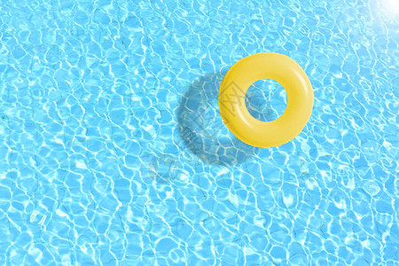黄色游泳池环漂浮在蓝水中图片