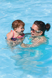 母亲和女儿在阳光明媚的夏日游泳池里玩水游泳培训健康生图片