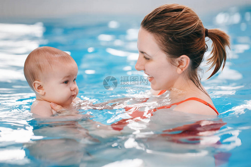 白种人母亲正在训练她刚出生的婴儿漂浮在游泳池里婴儿在水中潜水健康积极的生活方式家庭活动和图片