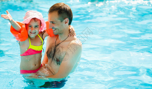 年轻快乐的父亲和他的小女儿在游泳池里图片