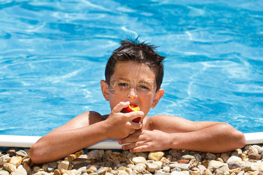 男孩在游泳池里吃水果图片