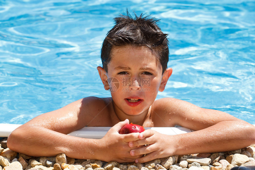 男孩在游泳池里吃水果图片