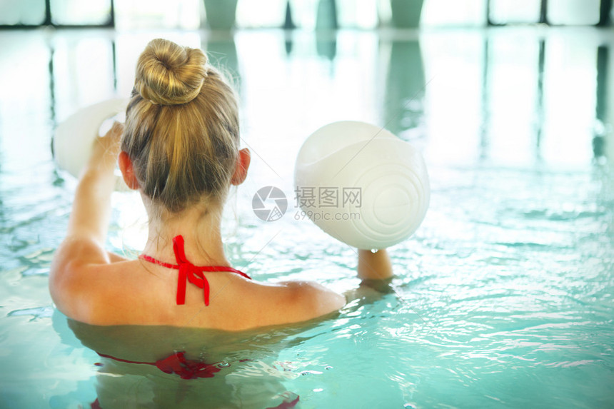 在休闲中心游泳池用泡沫哑铃做水有氧运动的Blon图片