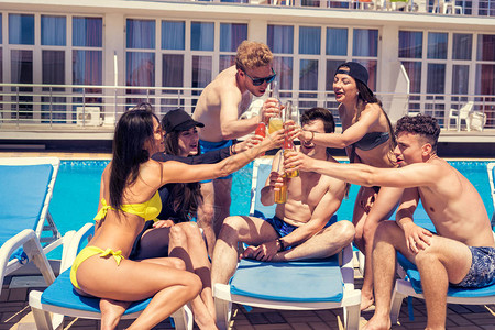 在泳池派对上喝鸡尾酒和啤酒的一群欢乐朋友图片