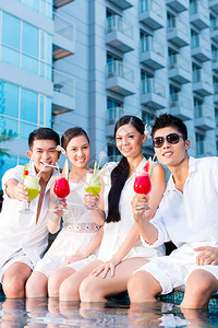 两对年轻英俊的亚洲华裔夫妇或朋友在豪华酒店泳池图片